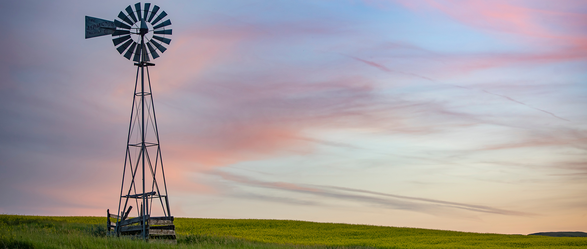 Windmill during sunset in a green field